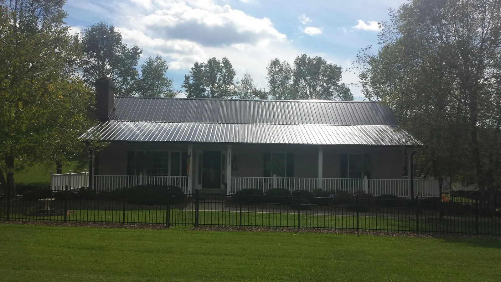 Gray metal roof on a brick ranch with a full width front porch — Gutter Guard Installation work by our crew in Cecil