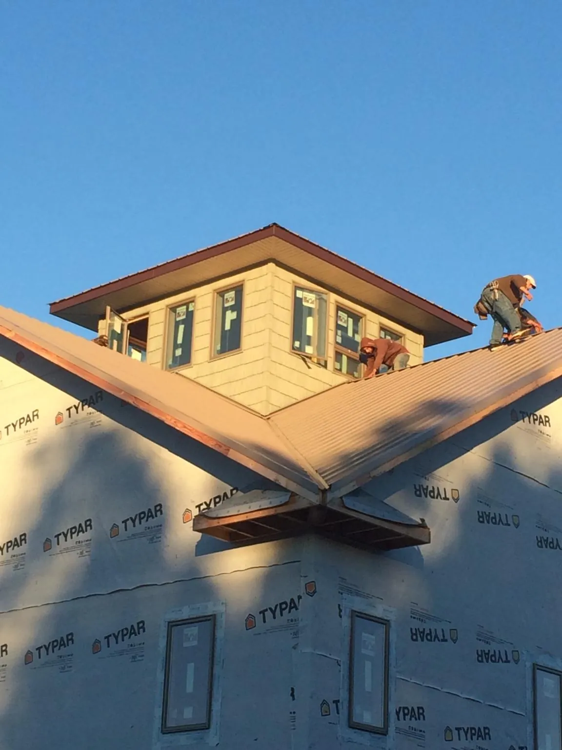 Roofers working around a rooftop cupola on a new metal roof at sunset — Roof Waterproofing in Cecil by Roofing Brothers